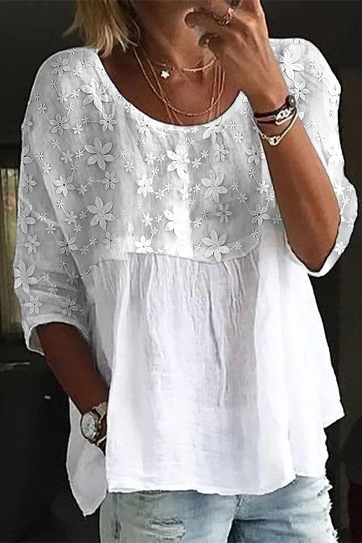 Elegante blusa da donna in cotone con vistose rientranze e applicazioni floreali, colletto classico e maniche lunghe