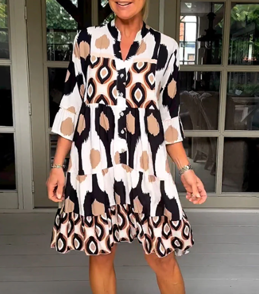 Abito da donna alla moda con bottoni sul davanti, taglio leggermente affusolato, maniche a tre quarti e motivo astratto di grande effetto.