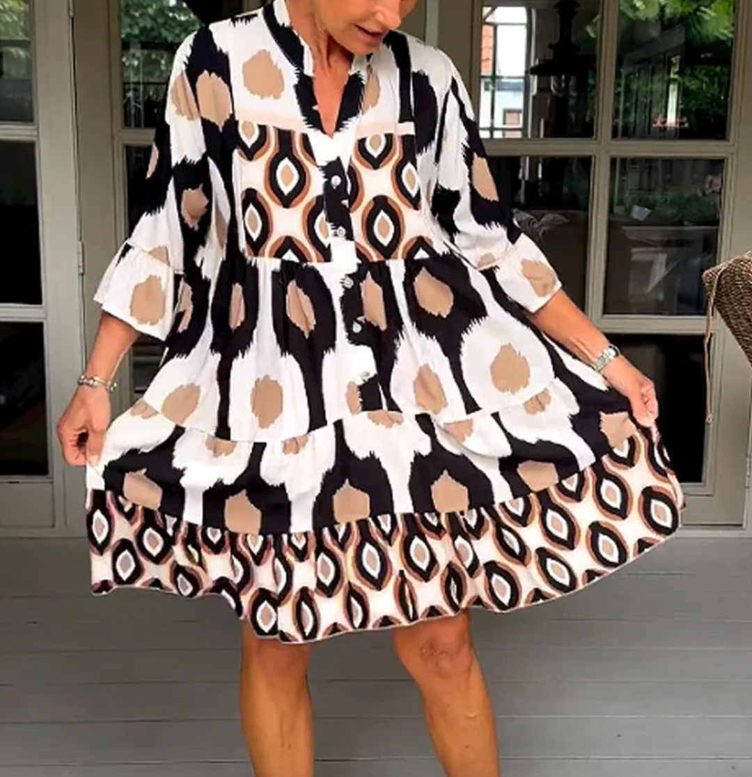 Abito da donna alla moda con bottoni sul davanti, taglio leggermente affusolato, maniche a tre quarti e motivo astratto di grande effetto.