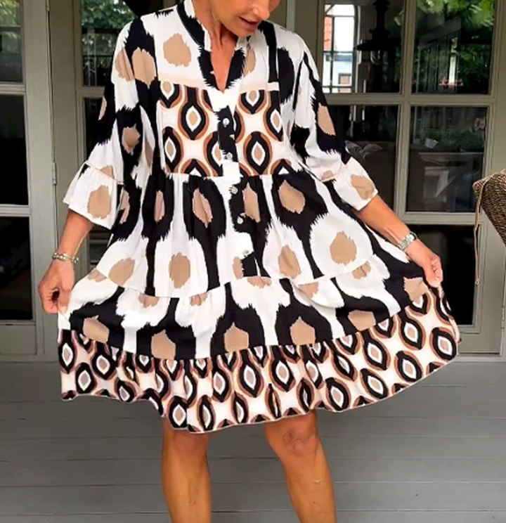 Abito da donna alla moda con bottoni sul davanti, taglio leggermente affusolato, maniche a tre quarti e motivo astratto di grande effetto.
