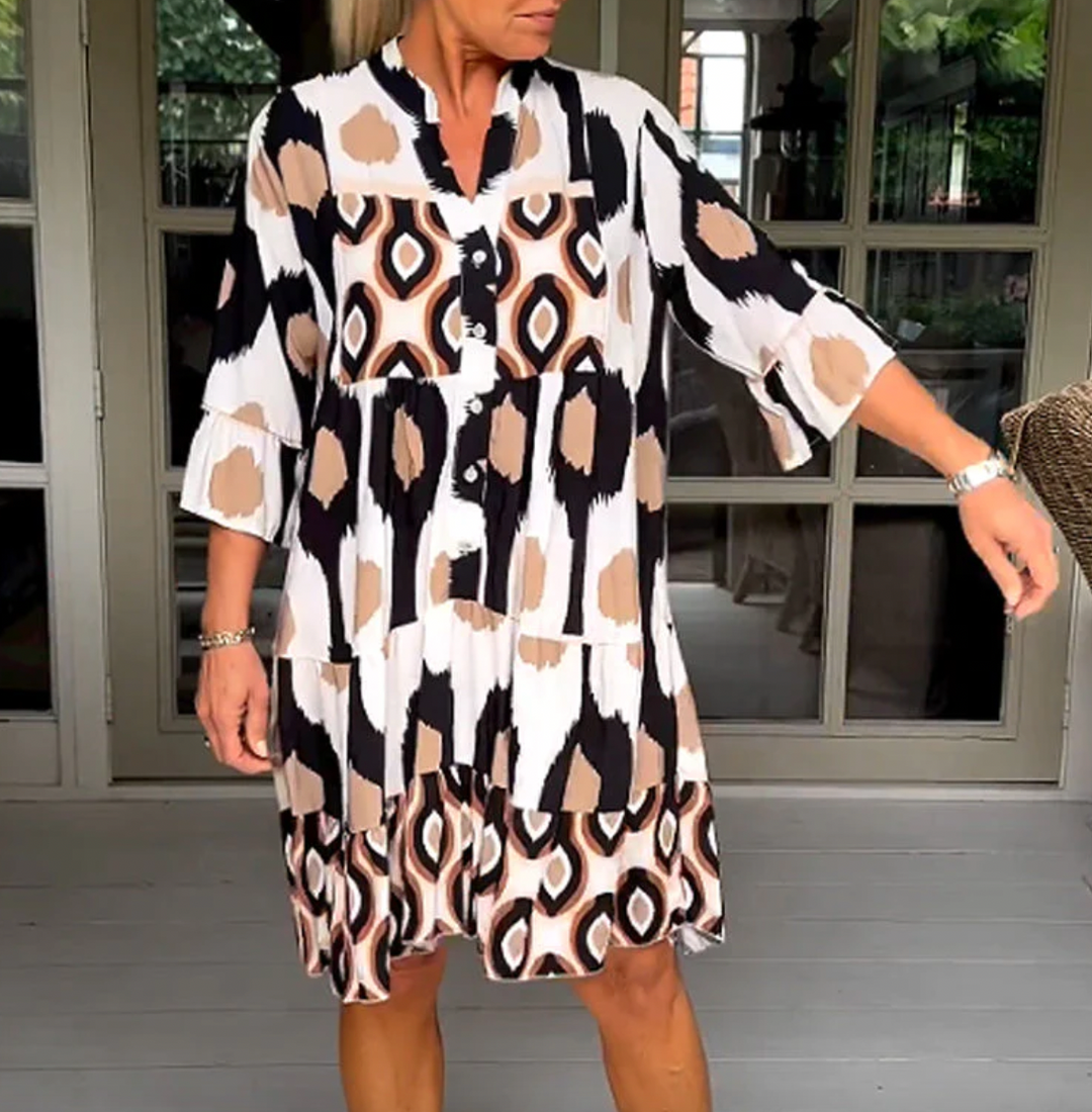 Abito da donna alla moda con bottoni sul davanti, taglio leggermente affusolato, maniche a tre quarti e motivo astratto di grande effetto.