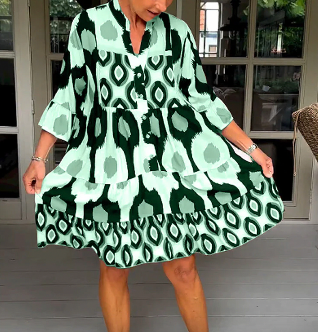 Abito da donna alla moda con bottoni sul davanti, taglio leggermente affusolato, maniche a tre quarti e motivo astratto di grande effetto.