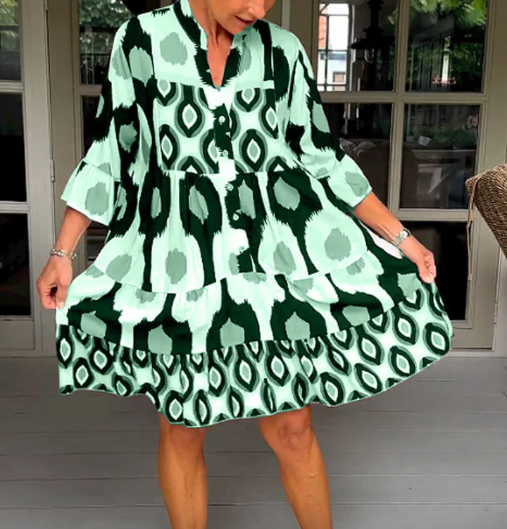 Abito da donna alla moda con bottoni sul davanti, taglio leggermente affusolato, maniche a tre quarti e motivo astratto di grande effetto.