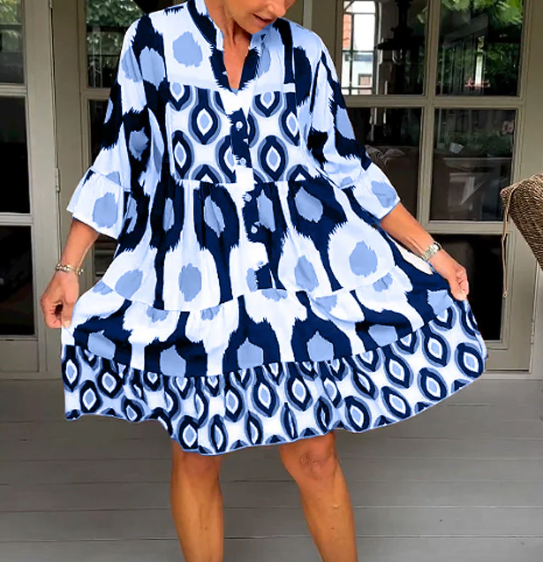 Abito da donna alla moda con bottoni sul davanti, taglio leggermente affusolato, maniche a tre quarti e motivo astratto di grande effetto.