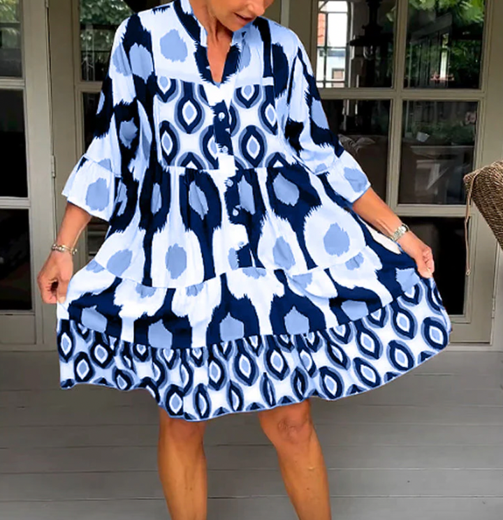 Abito da donna alla moda con bottoni sul davanti, taglio leggermente affusolato, maniche a tre quarti e motivo astratto di grande effetto.