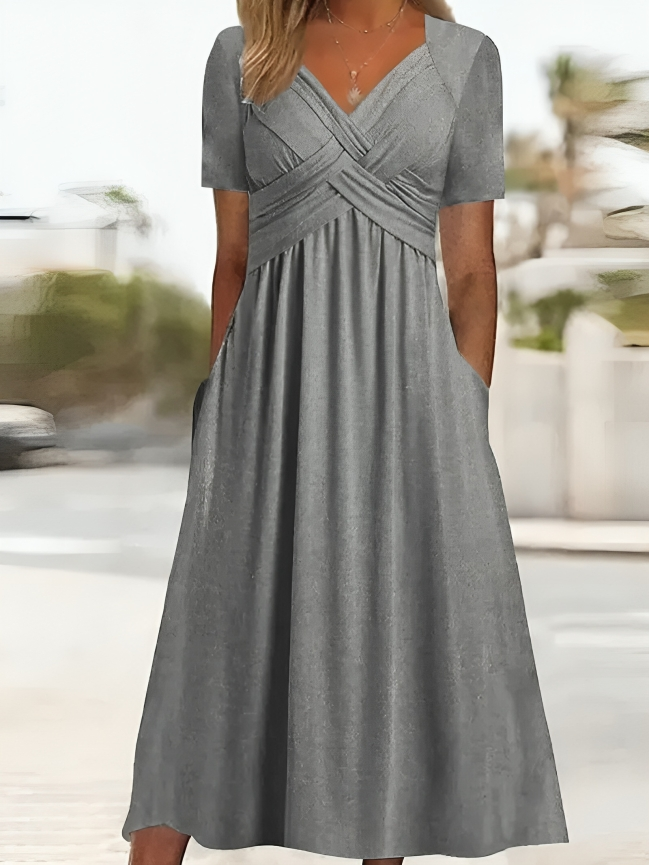 Elegante abito da donna dalla linea ad A, con vistosa scollatura incrociata, maniche corte, lunghezza al ginocchio e pratiche tasche
