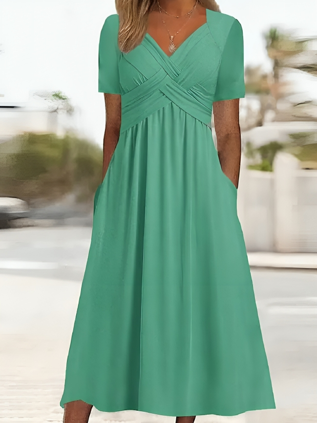 Elegante abito da donna dalla linea ad A, con vistosa scollatura incrociata, maniche corte, lunghezza al ginocchio e pratiche tasche